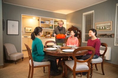 Family sitting around dinner table ready to eat | Host Family Stay